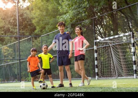 Happy young family playing football on soccer field Stock Photo