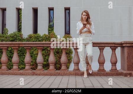 Young in white look using smartphone in the city, texting message, connect Stock Photo