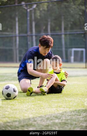 Father taking care of his injured daughter on soccer field Stock Photo