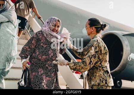 Sigonella, Italy. 22nd Aug, 2021. U.S. Navy Command Master Chief Anna Wood assists evacuees as they disembark from a U.S. Air Force C-17 Globemaster III aircraft after arrival at Naval Air Station Sigonella August 22, 2021 in Sigonella, Italy. NAS Sigonella is providing temporary lodging for evacuees from Afghanistan as part of Operation Allies Refuge. Credit: Planetpix/Alamy Live News Stock Photo