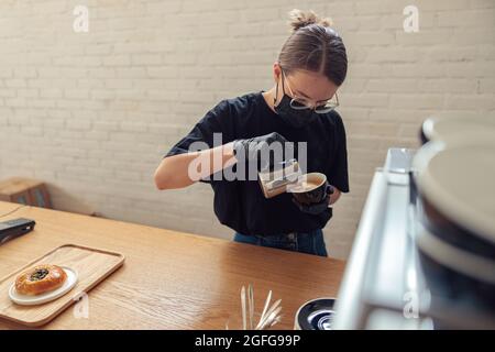 Woman making espresso from coffee machine in cafeteria Stock Photo