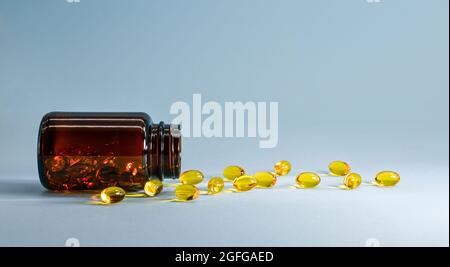Capsules roll from a glass jar on a blue surface. Stock Photo