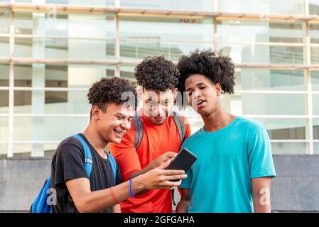 Multiethnic friends using mobile phone in the street Stock Photo