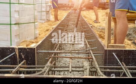 Pouring cement or concrete with automatic pump, construction site with reinforced grillage foundation, start of new house building construction. Stock Photo