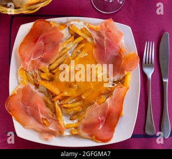 Fried eggs with fried potatoes and sliced cured ham Stock Photo