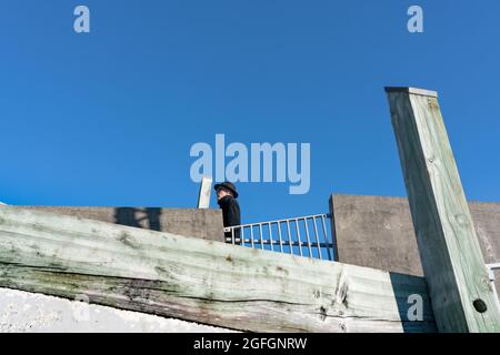 Wellington New Zealand - July 31 2021; One man in bowler hat walks along a bridge against sky Stock Photo