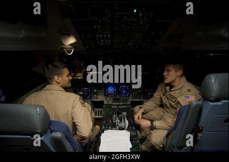 Capt. Travis Kuenzi and 1st Lt. Alexander Hanna, 816th  Expeditionary Airlift Squadron, chat as they prepare to conduct engine start up procedures on a C-17 Globemaster III prior to an air delivery mission. The C-17 aircrew air delivered cargo which consisted of fuel and other various supplies to a remote forward operating base in Afghanistan. Kuenzi and Hanna are deployed from the 7th Airlift Squadron, McChord Air Force Base, Wash. Stock Photo