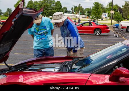 Admirers inspect the engine of a red C7 Chevrolet Corvette Stingray sports car on display in Angola, Indiana, USA. Stock Photo