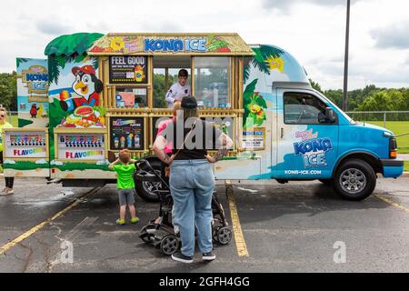 Customers wait in line to buy Kona Ice from a food vendor's colorful truck in Angola, Indiana, USA. Stock Photo