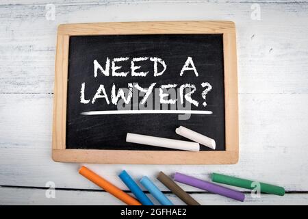 Need a Lawyer handwritten on blackboard. Chalk board on a painted wooden background. Stock Photo