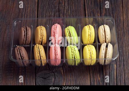 Colorful mini macaroons in a plastic box on old wooden table Stock Photo