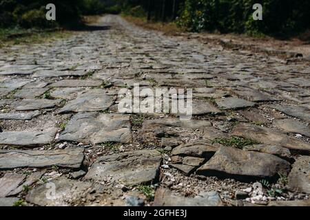 road in the mountains from a large brown cobblestone goes into the distance Stock Photo