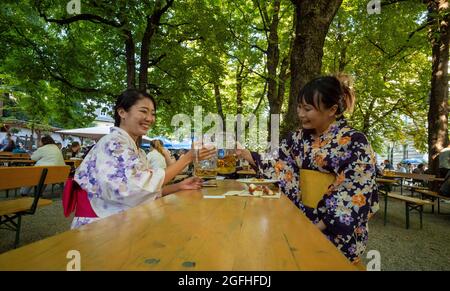 Munich, Germany. 25th Aug, 2021. The two Japanese women Sakura Suzuki (l) and Imho Uchitani, who are both from Tokyo, drink a Maß beer at Wiener Platz in traditional Japanese kimonos. Suzuki is studying in the Bavarian capital, while Uchitani accompanies her husband, who has come to Bavaria to work. Credit: Peter Kneffel/dpa/Alamy Live News Stock Photo