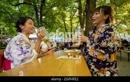 Munich, Germany. 25th Aug, 2021. The two Japanese women Sakura Suzuki (l) and Imho Uchitani, who are both from Tokyo, drink a Maß beer at Wiener Platz in traditional Japanese kimonos. Suzuki is studying in the Bavarian capital, while Uchitani accompanies her husband, who has come to Bavaria to work. Credit: Peter Kneffel/dpa/Alamy Live News Stock Photo