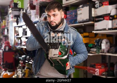 male is standing with new chainsaw in tools store Stock Photo