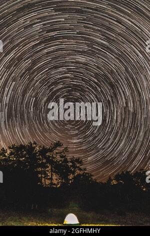 Astrophotographical photo of startrail over tree top at night and pointing at the north Stock Photo