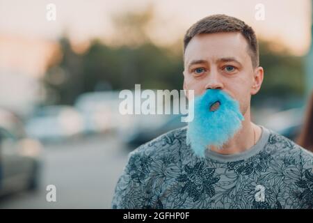 Young adult man with beard made of blue cotton candy Stock Photo