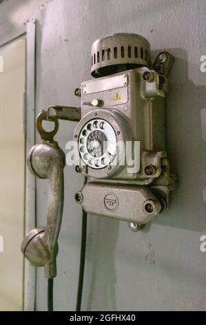 Old vintage wired telephone for communication hangs on textured gray wall. Antique phone from past for background Stock Photo