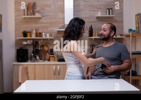 Upset wife caught cheating by jealous husband holding smartphone for