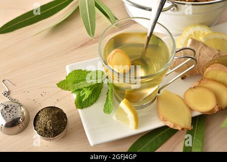 Cup of green tea with ginger lemon and mint on wooden table with leaves on wooden table. Elevated view. Stock Photo