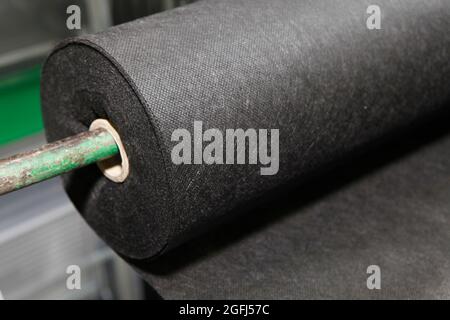 A close-up on black biodegradable polypropylene saturated bonded spunbond, spunlaid non woven fabric roll. Stock Photo