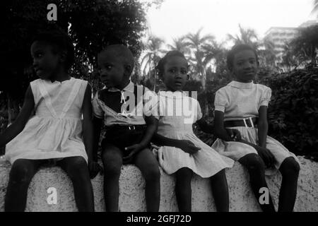 Kinder in Sonntagstracht sitzen auf einer Mauer, Port-au-Prince, Haiti, 1966. Children in their Sunday dresses sitting on a wall, Port-au-Prince, Haiti, 1966. Stock Photo