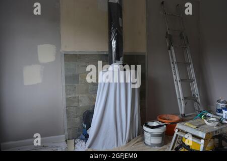 Room being redecorated, walls prepared for painting, and stove covered for protection Stock Photo