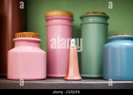 Selection of colorful handmade ceramic or pottery kitchen containers on a shelf with selective focus to a pink salt shaker in the foreground in close Stock Photo