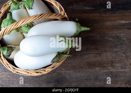 Harvest white eggplants on a wooden background with place for text. Eggplant vegetable on the table. Food with copy space Stock Photo