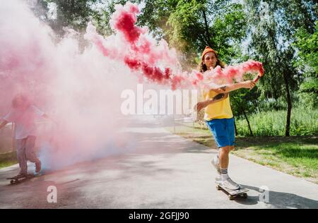 skaters with colored smoke bombs. Professional skateboarders having fun at the skate park Stock Photo