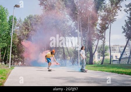 skaters with colored smoke bombs. Professional skateboarders having fun at the skate park Stock Photo