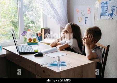 Schoolkids boy and girl using laptop for online study during homeschooling at home. Homeschooling, online study, home quarantine online learning Stock Photo