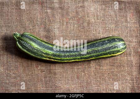 Fresh striped zucchini on sackcloth background with copy space. Flat lay, top view. Rustic style Stock Photo