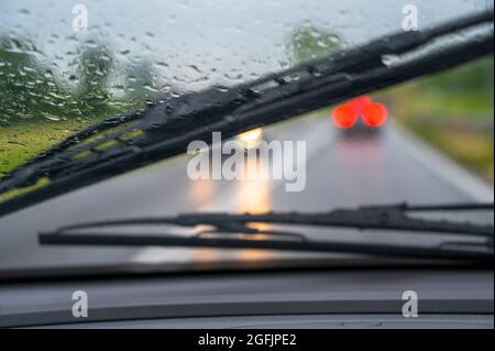 Drops of rain on windscreen of a car driving in the rain. Stock Photo