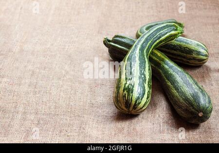 Fresh striped zucchini on sackcloth background with copy space Stock Photo