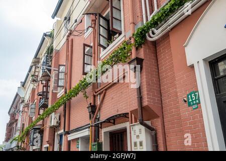Shanghai, Shanghai, China. 26th Aug, 2021. On August 26, 2021, on both sides of Jiangyin Road in Huangpu District, Shanghai, there are mostly two-story Shikumen Lane houses. There are a lot of green vines along the outer wall of the street, which is nothing special at first glance. Observing carefully, these green leaves are actually simulated leaves with some wires that cannot be hidden inside. Compared with the black wires, this decoration looks much more beautiful. Visual pollution of various overhead lines in old communities is often difficult to deal with. However, in the blocks of Stock Photo