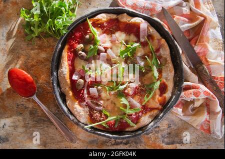 Pizza base with whole wheat flour with arugula and onion Stock Photo