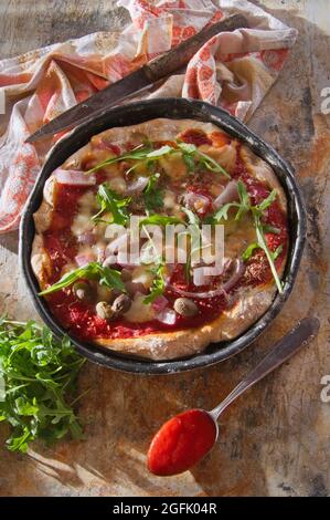 Pizza base with whole wheat flour with arugula and onion Stock Photo