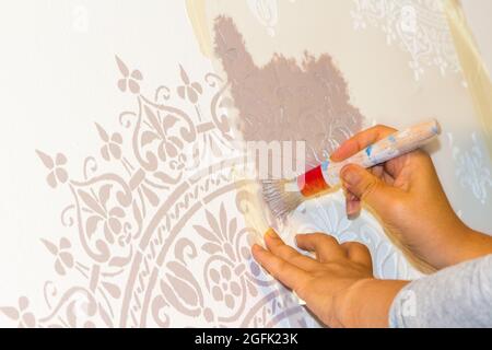 Painting stencil shapes on wall of room at home Stock Photo