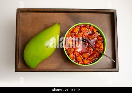 Raw Mango and Kairi and Mango Pickle Achar placed on a wooden Tray Studio Shot Stock Photo