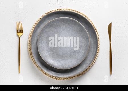 Elegance table setting with empty gray plate with golden cutlery as mockup on white. Top view. Stock Photo