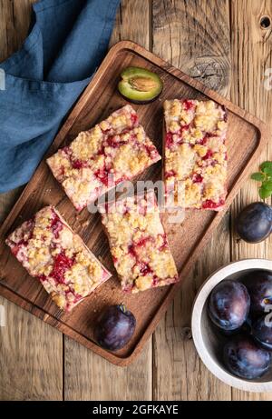 Juicy plum pie slices with crunchy streusel topping on rustic wooden background Stock Photo
