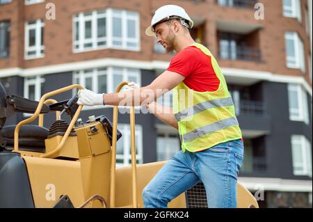 Concentrated skilled worker in a safety helmet using construction equipment Stock Photo
