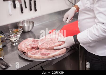 Cropped shot of a professional chef preparing marbled raw beef meat for grilling Stock Photo
