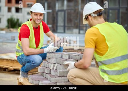 Two skilled workers in cotton gloves selecting external paving materials Stock Photo