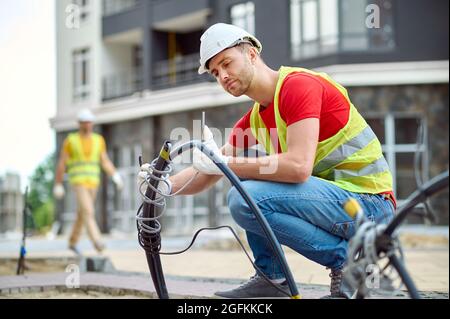 Concentrated skilled construction worker in cotton gloves installing electricity Stock Photo