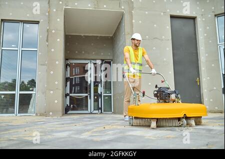 Joyous man in cotton gloves cleaning the outdoor floor tiles Stock Photo