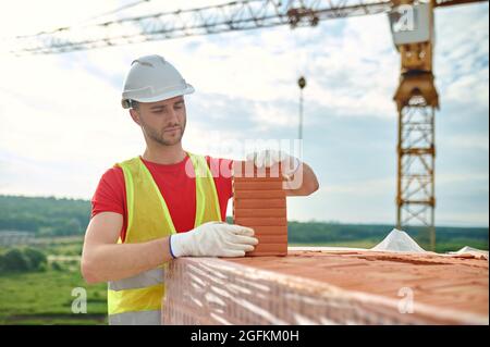 Focused experienced builder testing a perforated red brick Stock Photo