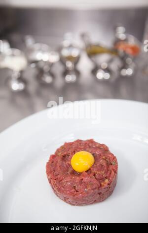 Vertical close up of beef tartar with raw quail egg on top, copy space Stock Photo