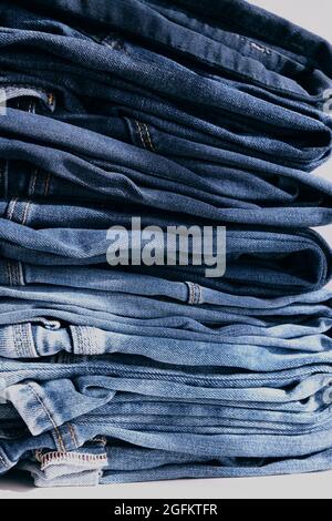 a pile of blue jeans on a grey background. Close up Stock Photo